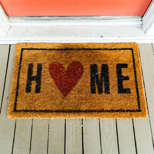 Doormat with the word home, the O in home is replaced with a heart
