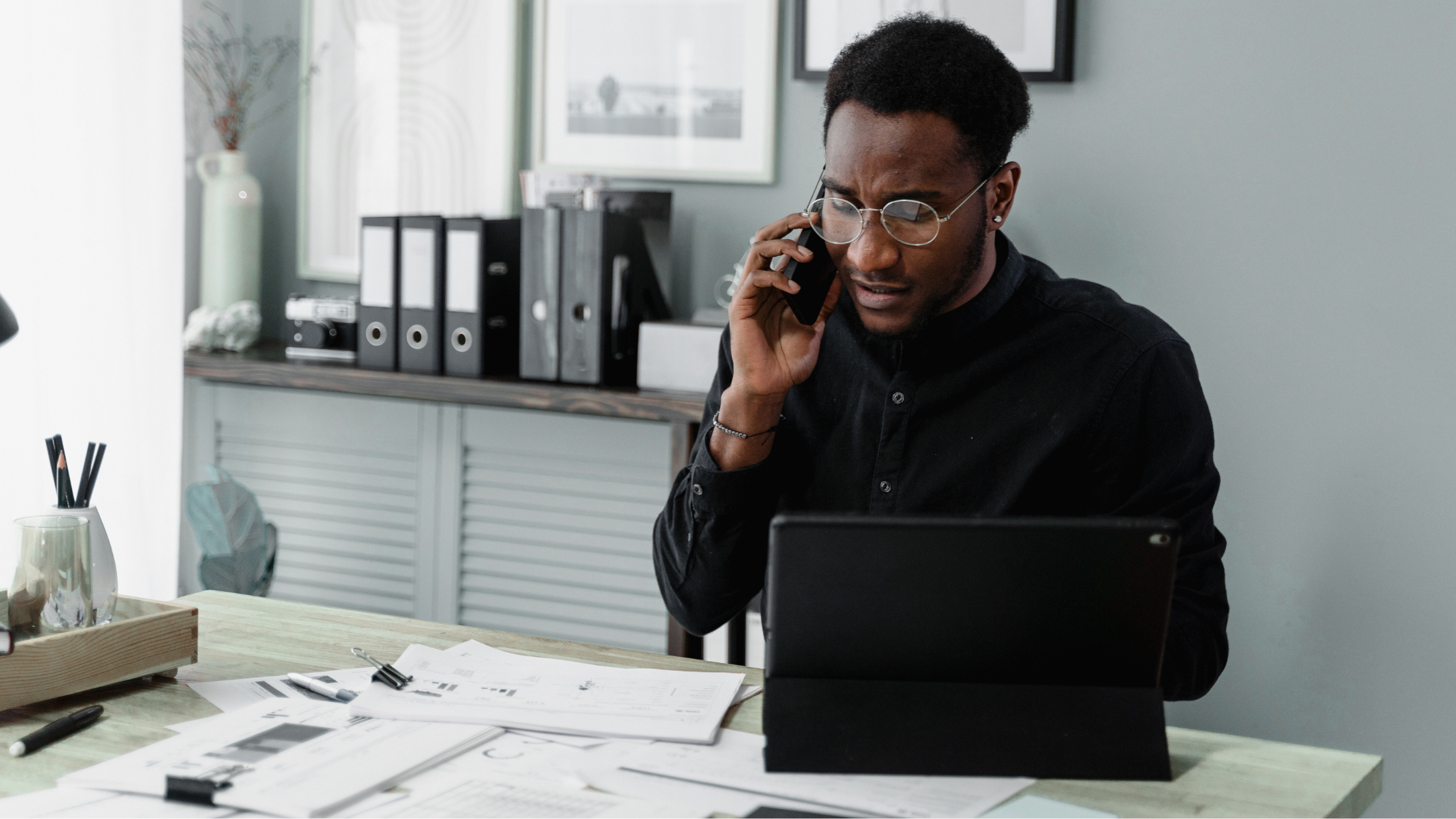 man on the phone at his desk, overwhelmed with paperwork
